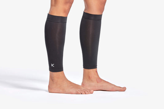Black compression leg sleeves on a person's legs against a white background