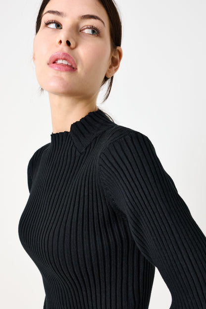 Woman wearing a black ribbed sweater against a white background