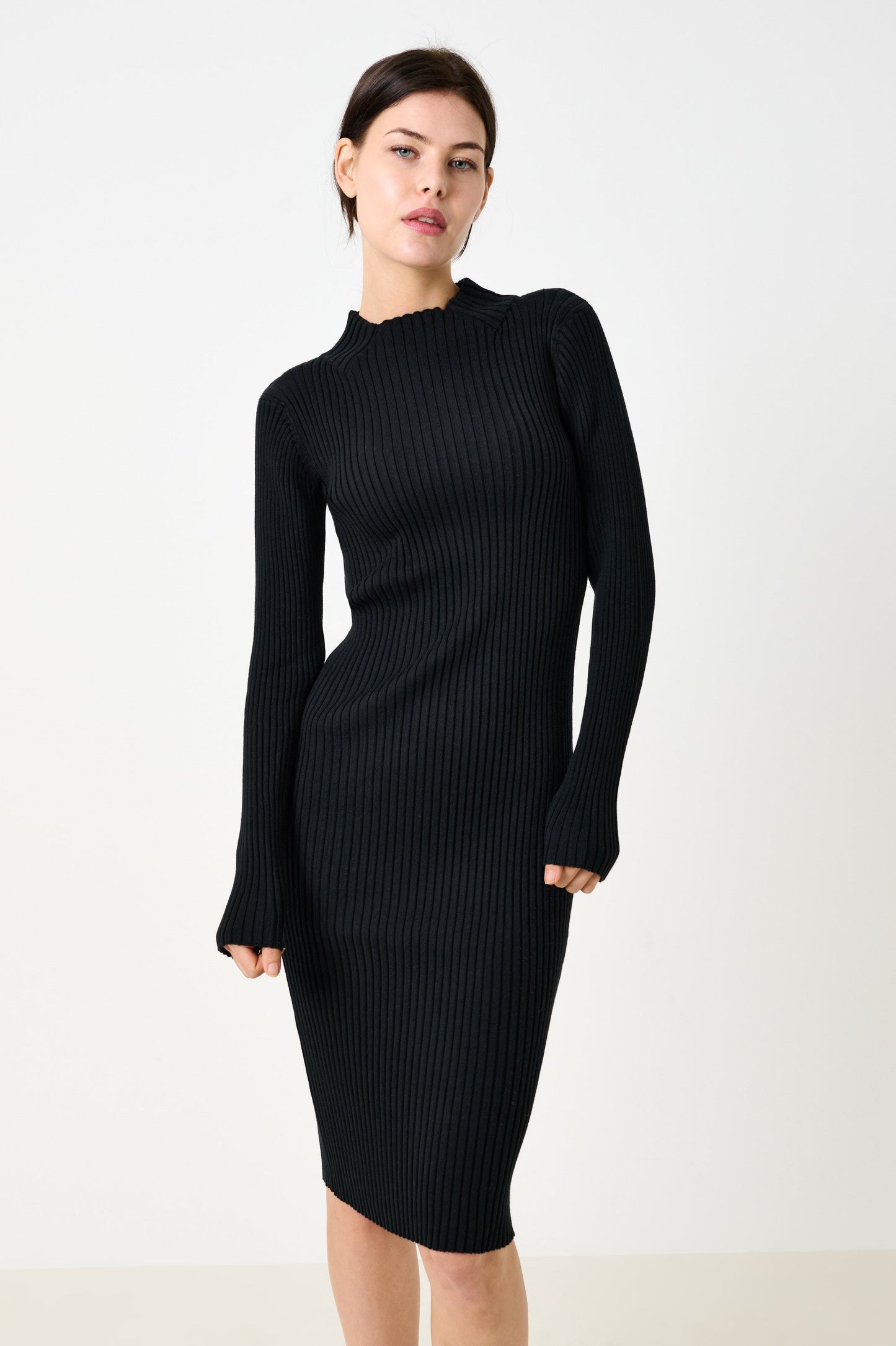 Woman wearing a black ribbed dress against a white background