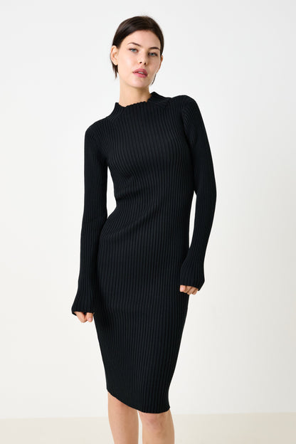 Woman wearing a black ribbed dress against a white background