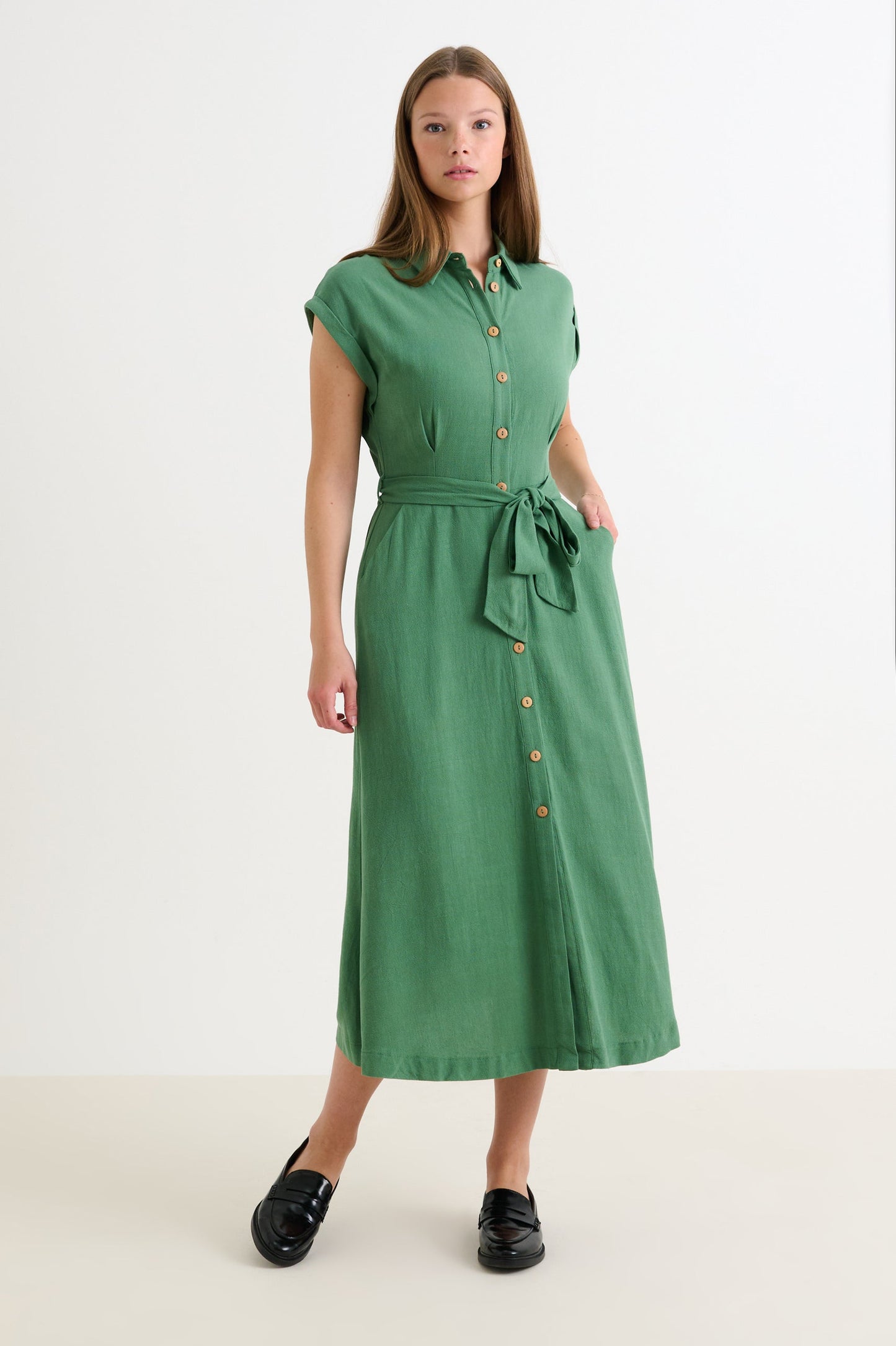 Woman wearing a green dress with a belt on a white background