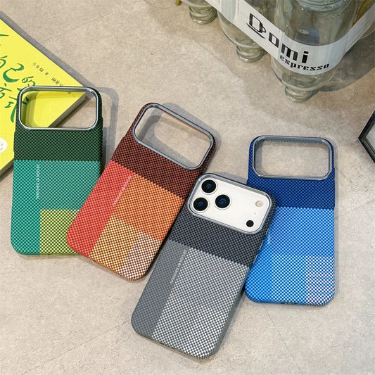 Four colorful phone cases on a textured surface with a bottle in the background.