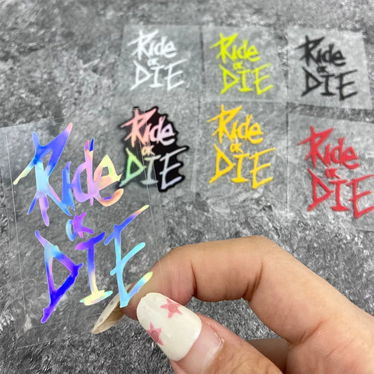 Colorful 'Ride or Die' stickers held by a hand on a gray background