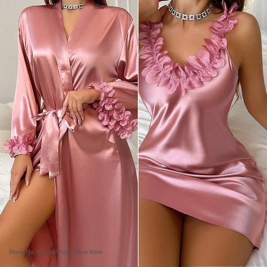 Pink satin robe with floral details worn by a model on a bed.