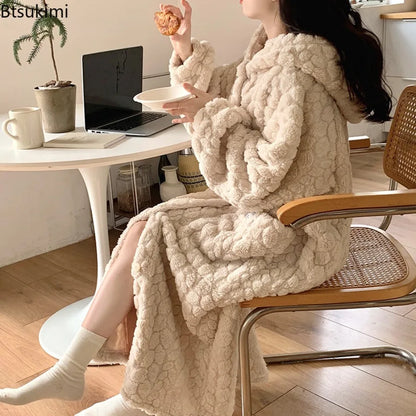 Person sitting on a chair wearing a fluffy beige blanket draped over their lap, with a laptop and cup on a table in the background.