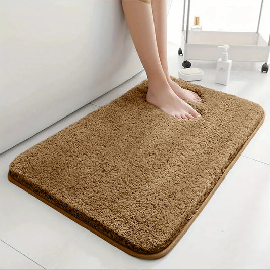 Brown bath mat on a bathroom floor with a person stepping onto it.