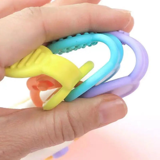 Colorful baby teething ring held in a hand against a white background