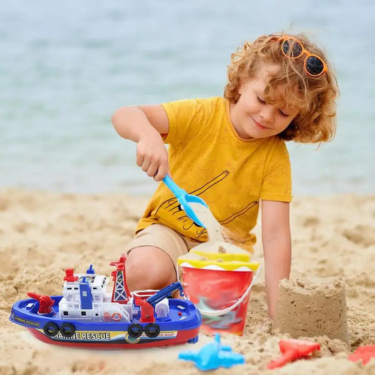 Child playing with a toy fireboat on a sandy beach