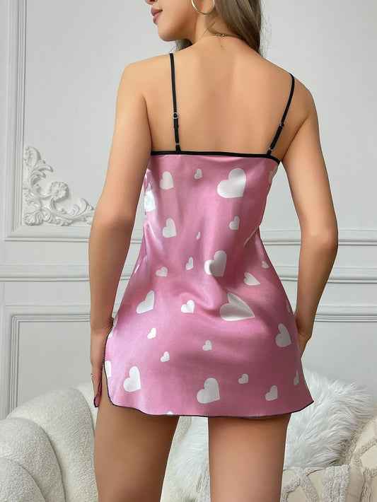 Pink satin nightgown with white heart patterns worn by a model against a neutral background.