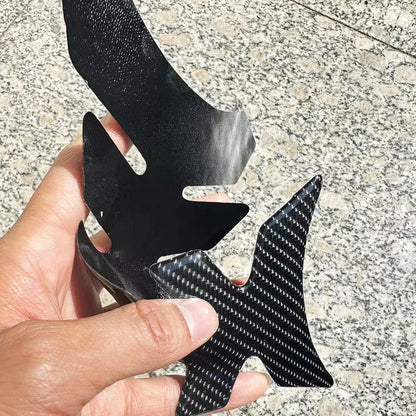 Carbon fiber winglet held by a hand on a textured surface