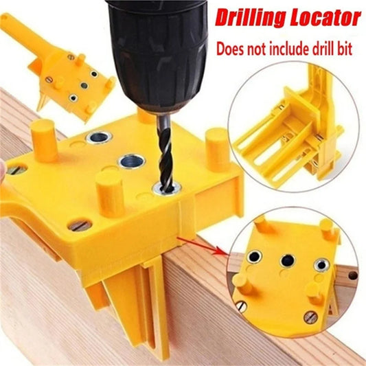 Yellow drilling locator tool with drill bit on a wooden surface, showing close-up details.