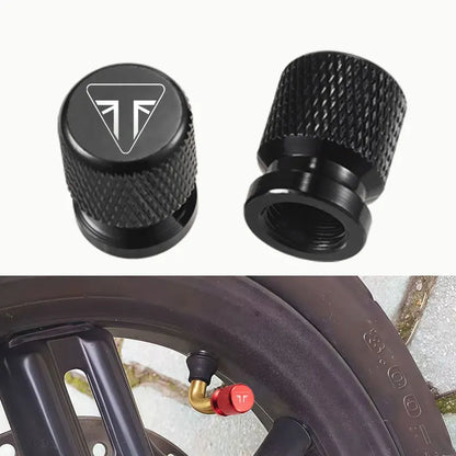 Two black valve stem caps with a logo on a white background, one cap is shown on a tire.