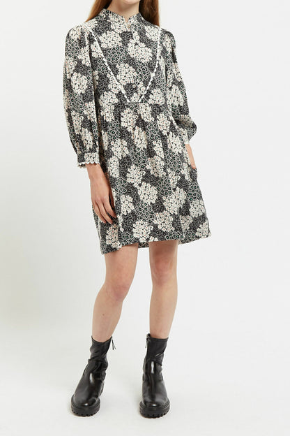 Person wearing a black and white floral dress with long sleeves on a white background