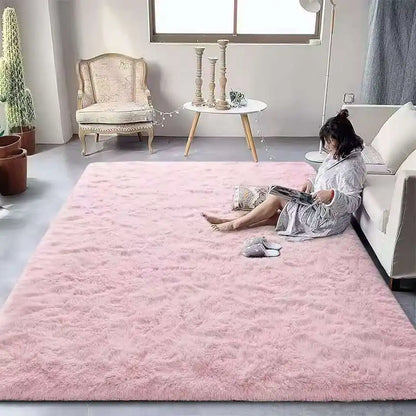 Woman sitting on a pink rug in a living room with a white sofa and decorative items.