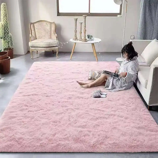 Woman sitting on a pink rug in a living room with a white sofa and decorative items.
