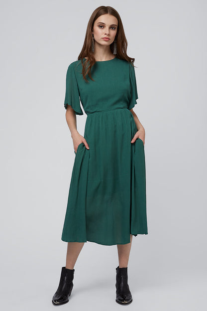 Woman wearing a green dress on a gray background
