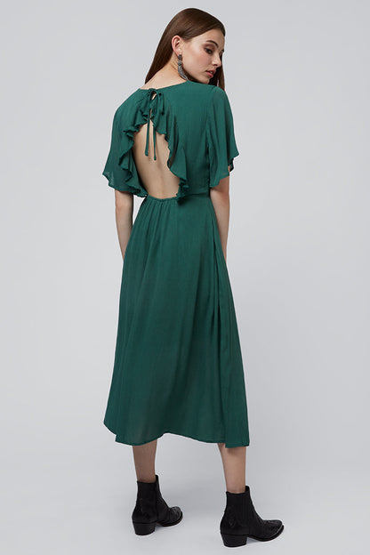 Woman wearing a green dress with open back on a white background
