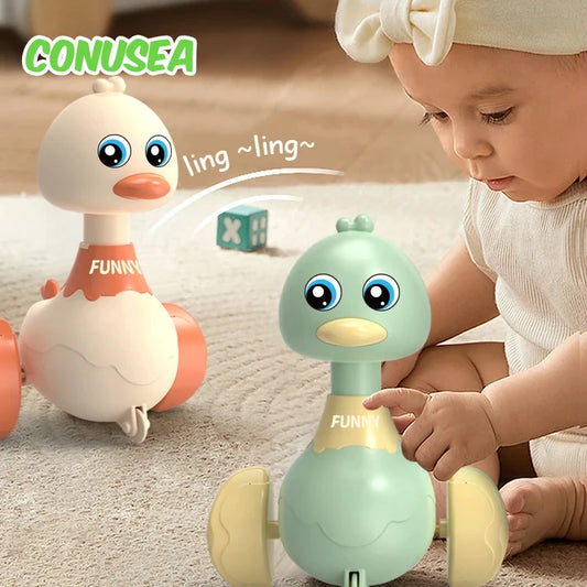 Child playing with a green toy duck, with another toy duck in the background, on a light-colored surface.
