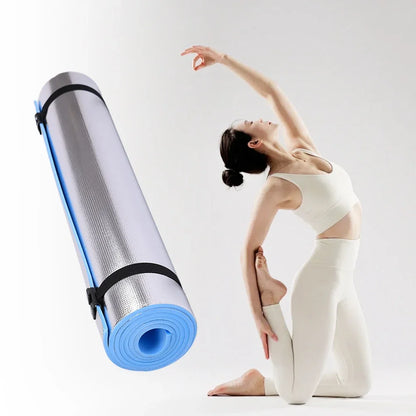 Yoga mat with carrying strap next to a person in a yoga pose on a white background