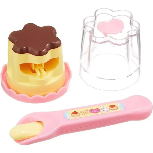 Toy set with a cake-shaped mold, clear container, and pink spoon on a white background