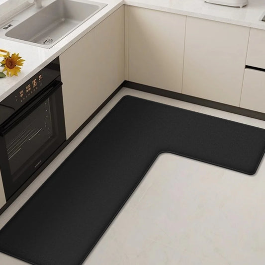 Black L-shaped kitchen mat on a white floor in a kitchen setting.