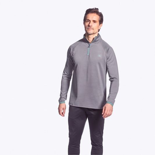 Man wearing a gray long-sleeve athletic shirt and dark pants on a white background