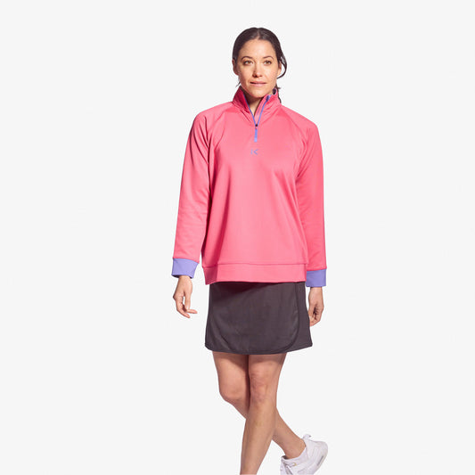 Woman wearing a pink pullover with a quarter zip and gray skirt on a white background