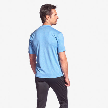 Man wearing a light blue t-shirt and dark pants on a white background