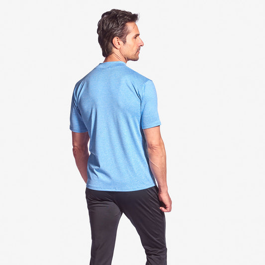 Man wearing a light blue t-shirt and dark pants on a white background