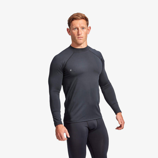 Man wearing a dark gray long-sleeve athletic shirt and pants on a white background