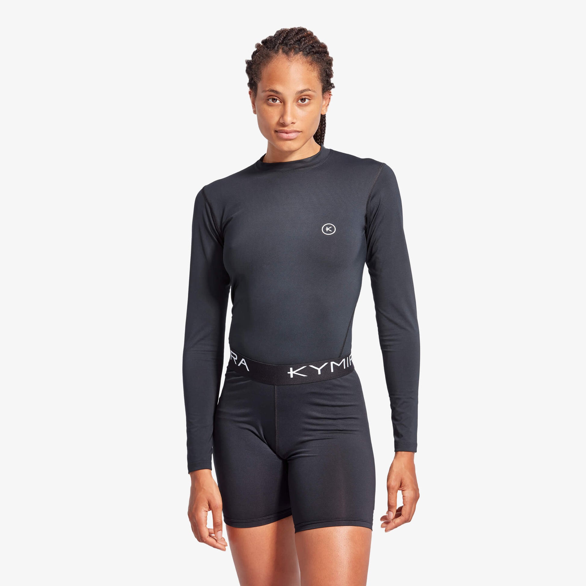 Person wearing a black long-sleeve athletic outfit with 'Kyma' branding on a white background