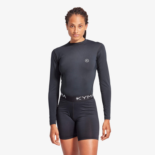 Person wearing a black long-sleeve athletic outfit with 'Kyma' branding on a white background