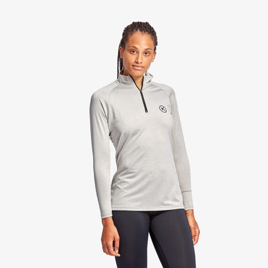 Woman wearing a gray long-sleeve athletic top with a logo on a white background