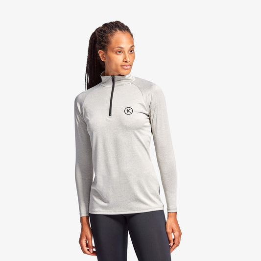 Woman wearing a gray long-sleeve athletic top with a brand logo on a white background