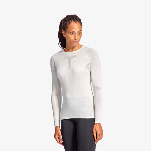 Woman wearing a white long-sleeve top and dark pants on a white background