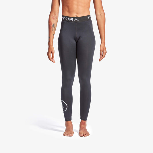 Person wearing dark gray leggings with a brand logo on a white background