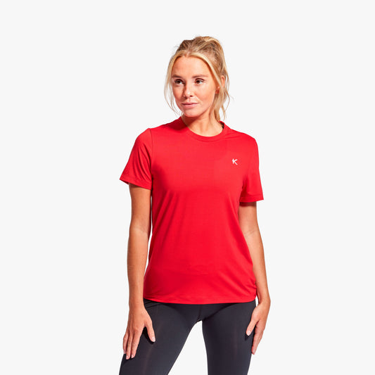 Woman wearing a red athletic shirt with a logo on a white background