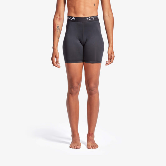 Person wearing black athletic shorts with a visible brand logo on a white background