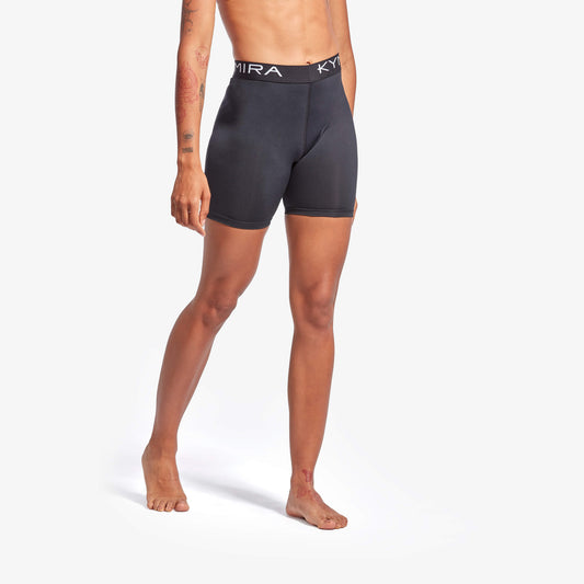 Person wearing black athletic shorts with a brand logo on a white background
