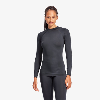 Woman wearing a black long-sleeve athletic top and leggings on a white background