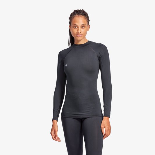 Woman wearing a black long-sleeve athletic top and leggings on a white background