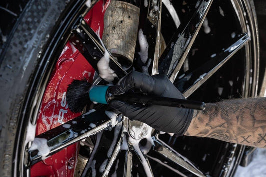 Person cleaning a motorcycle wheel with a brush