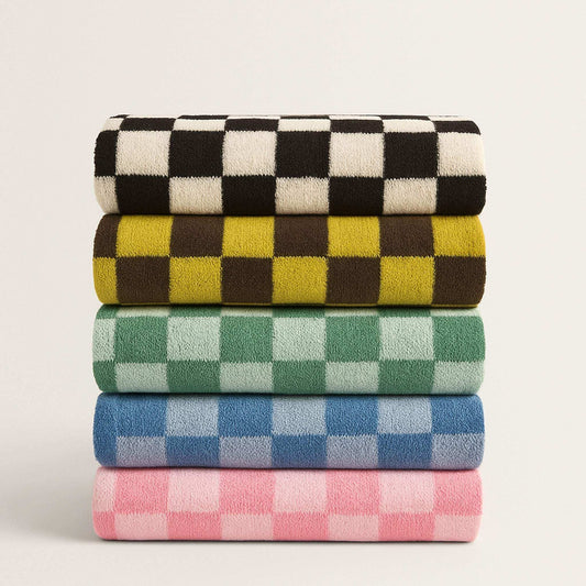 Stack of four checkered towels in black, yellow, green, and pink on a light gray background
