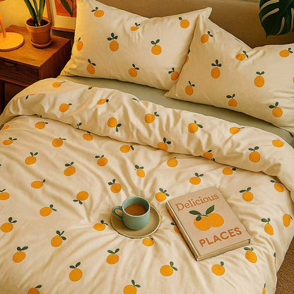 Bedding set with orange pattern on a bed with a cup and book.