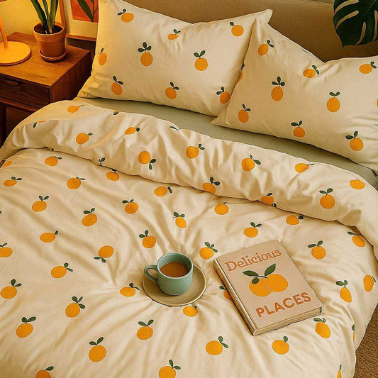 Bedding set with orange pattern on a bed with a cup and book.
