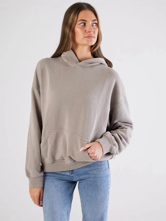 Woman wearing a beige hoodie and blue jeans on a white background