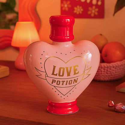 Heart-shaped bottle labeled 'Love Potion' on a wooden surface with a warm background.