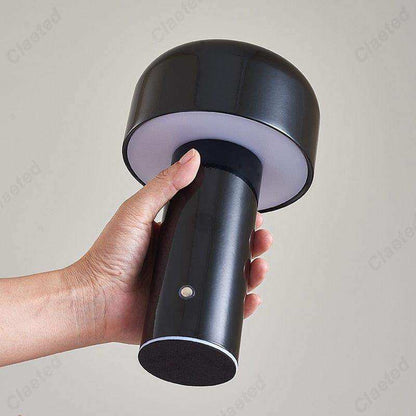 Black handheld lamp held by a hand against a gray background