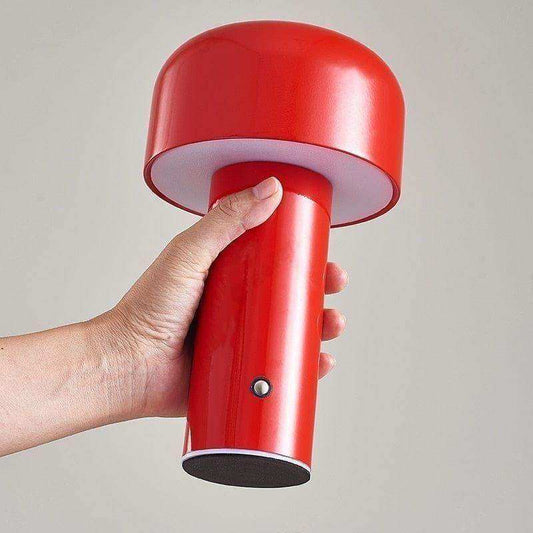 Red handheld lamp held by a hand against a plain background
