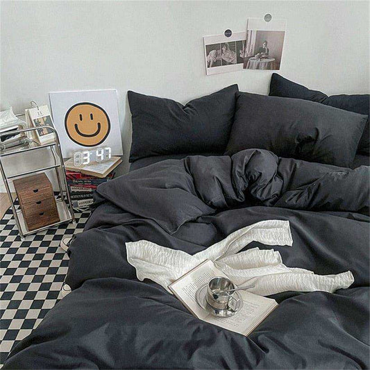 Black bedding set on a bed with a checkered floor and wall decorations.